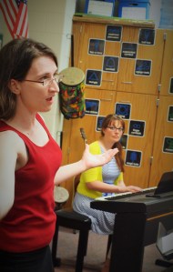 : Pictured left to right: Director Beverly Warkulwiz and Pianist Amber Faulhaber work with the singers to improve sections of songs.